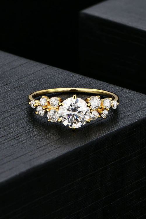 Close-up of a modern moissanite promise ring showing the cluster side stones and elegant gold-plated band.